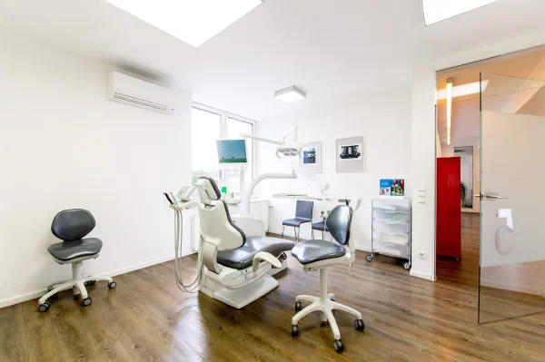 Behandlungszimmer mit Zahnarztstuhl, Fenster und Glastür zum Flur